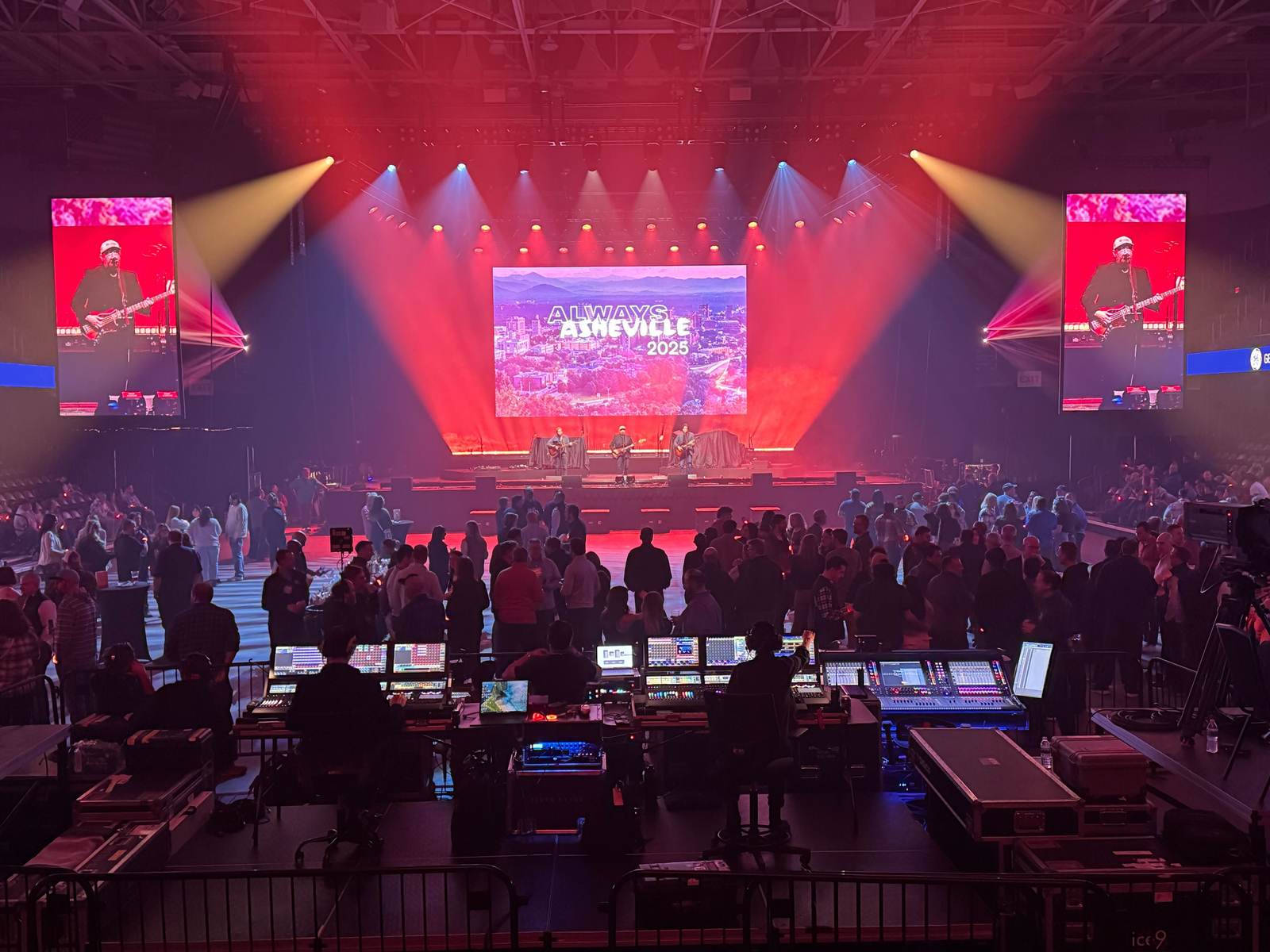 Arena show with red beam lighting, center screen and two vertical LED screens
