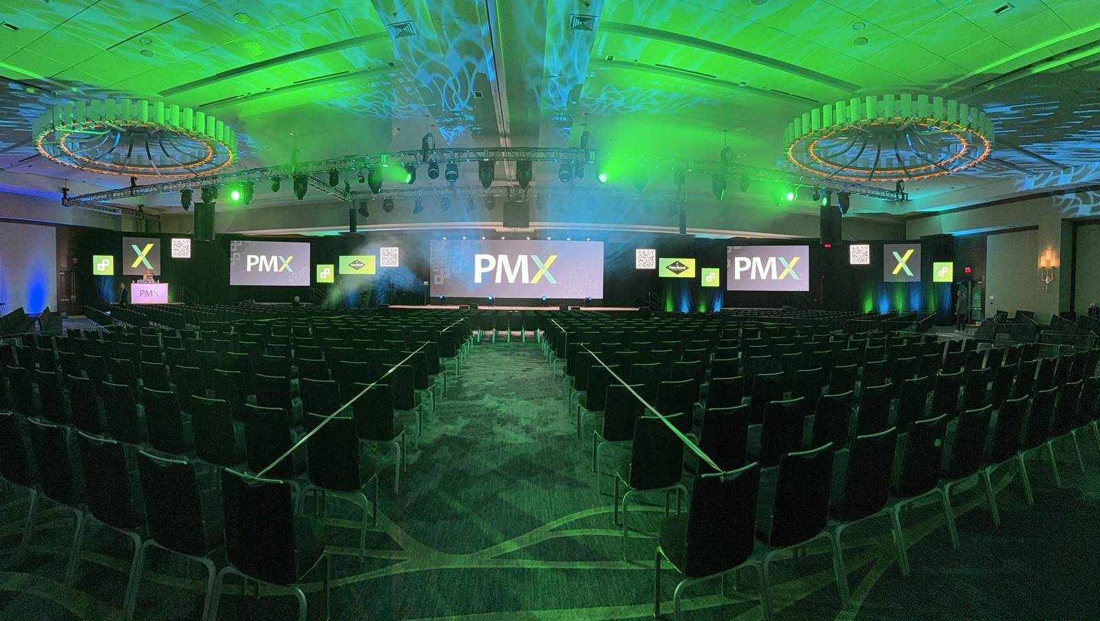 General session ballroom with center LED, flanking screens and green moving-light wash